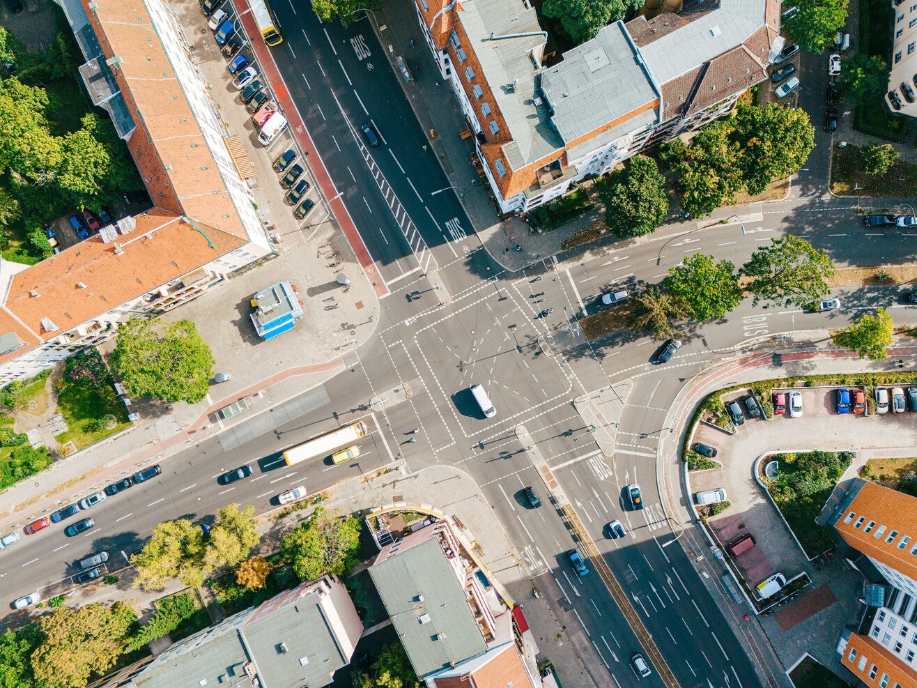 Luftaufnahme einer großen Straßenkreuzung mit Wohnhäusern und begrünten Innenhöfen in Berlin.