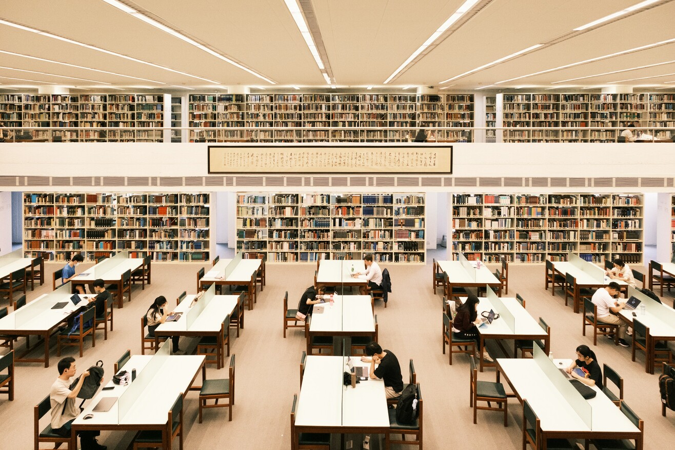 Großer Bibliotheksraum mit hohen Bücherregalen und zahlreichen Büchern.