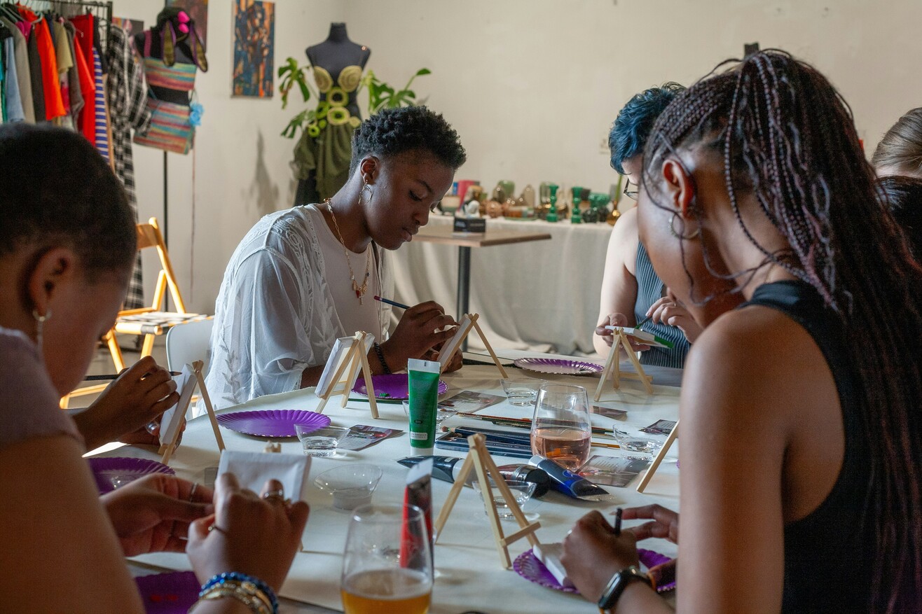 Mehrere Personen sitzen gemeinsam an einem Tisch und malen während eines kreativen Workshops.